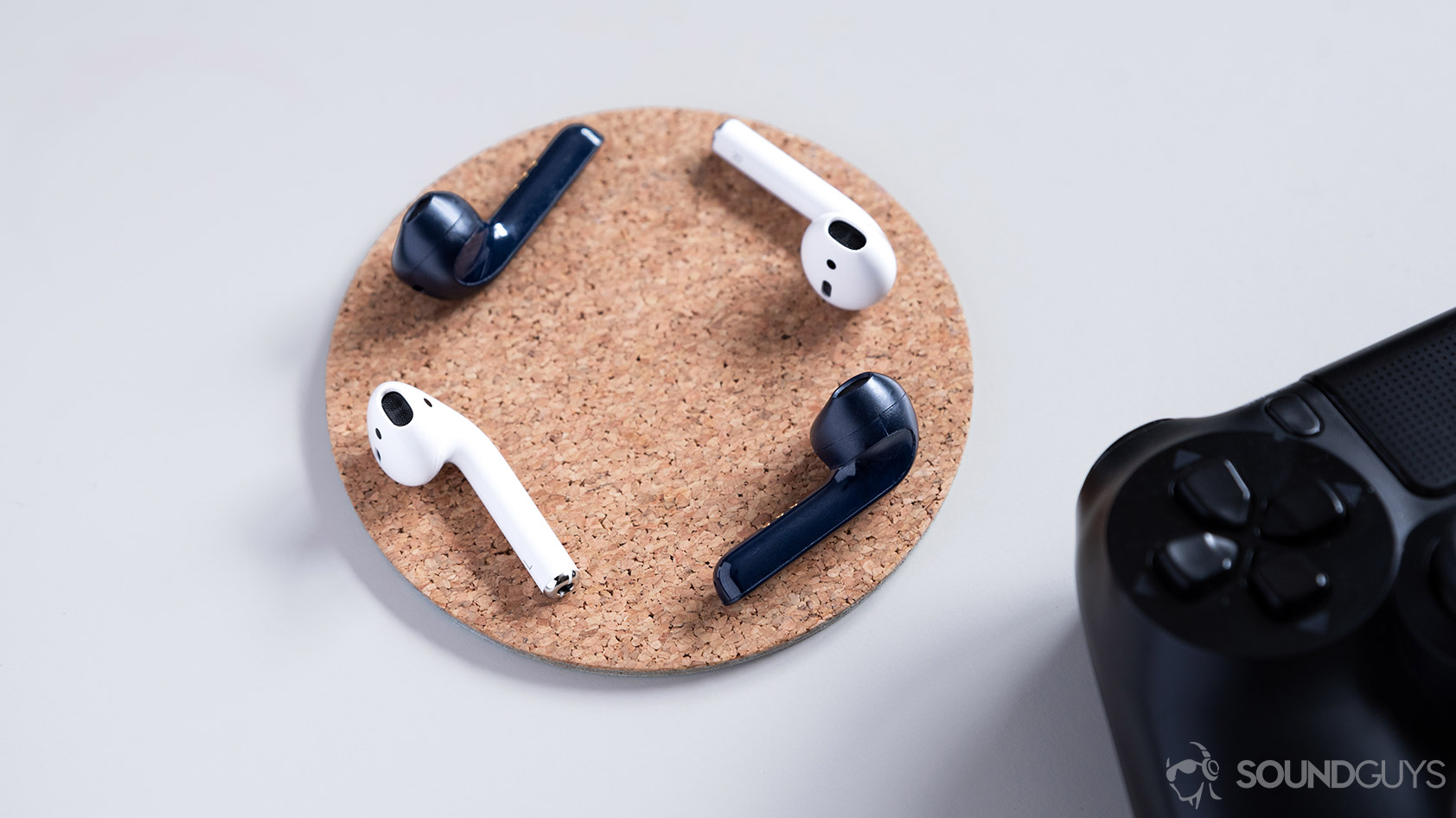 Mobvoi_TicPods 2 Pro-true wireless earbuds comparison Apple AirPods Mobvoi TicPods 2 Pro true wireless earbuds compared to the Apple AirPods on a cork coaster.