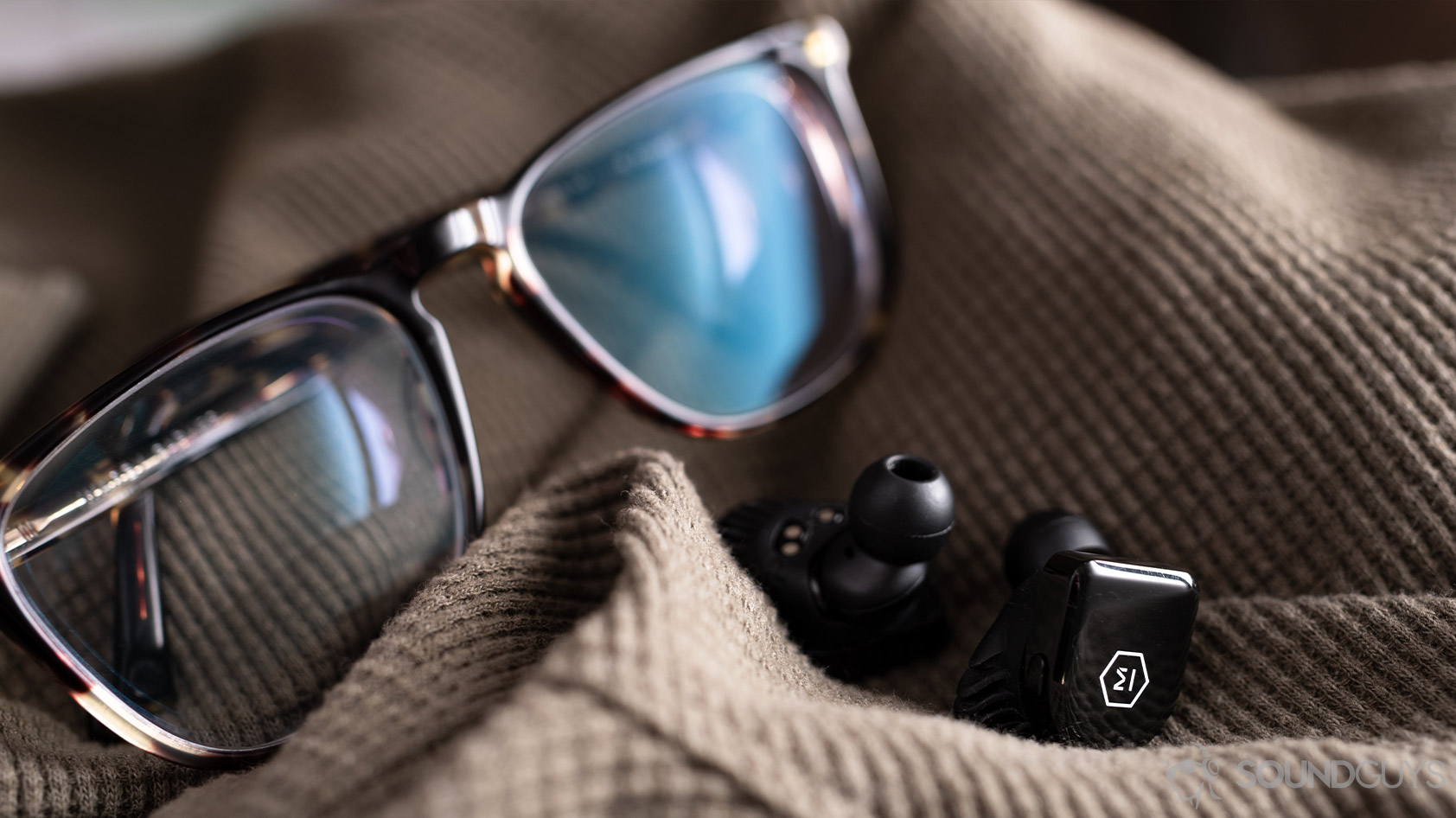 earbuds glasses-Master & Dynamic MW07 Go true wireless A picture the Master & Dynamic MW07 Go true wireless earbuds in front of Warby Parker tortoise shell glasses.