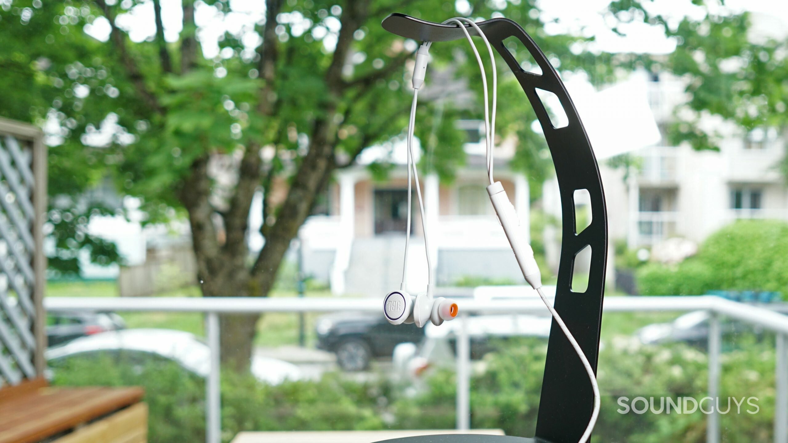 JBL-Quantum-50-feature-shot The JBL Quantum 50 wired gaming earbuds dangle from a black, curved headphone stand.