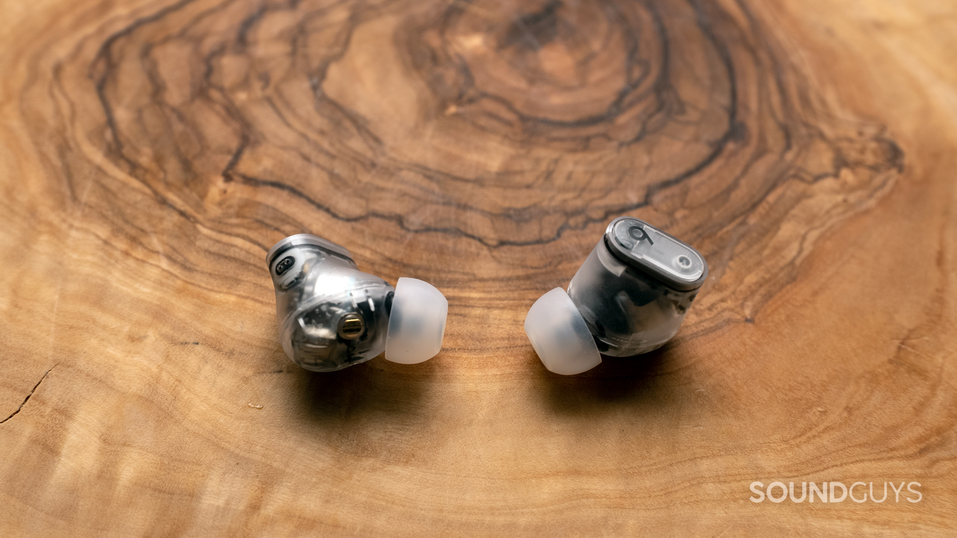 The Beats Studio Buds Plus earbuds against a wooden surface.