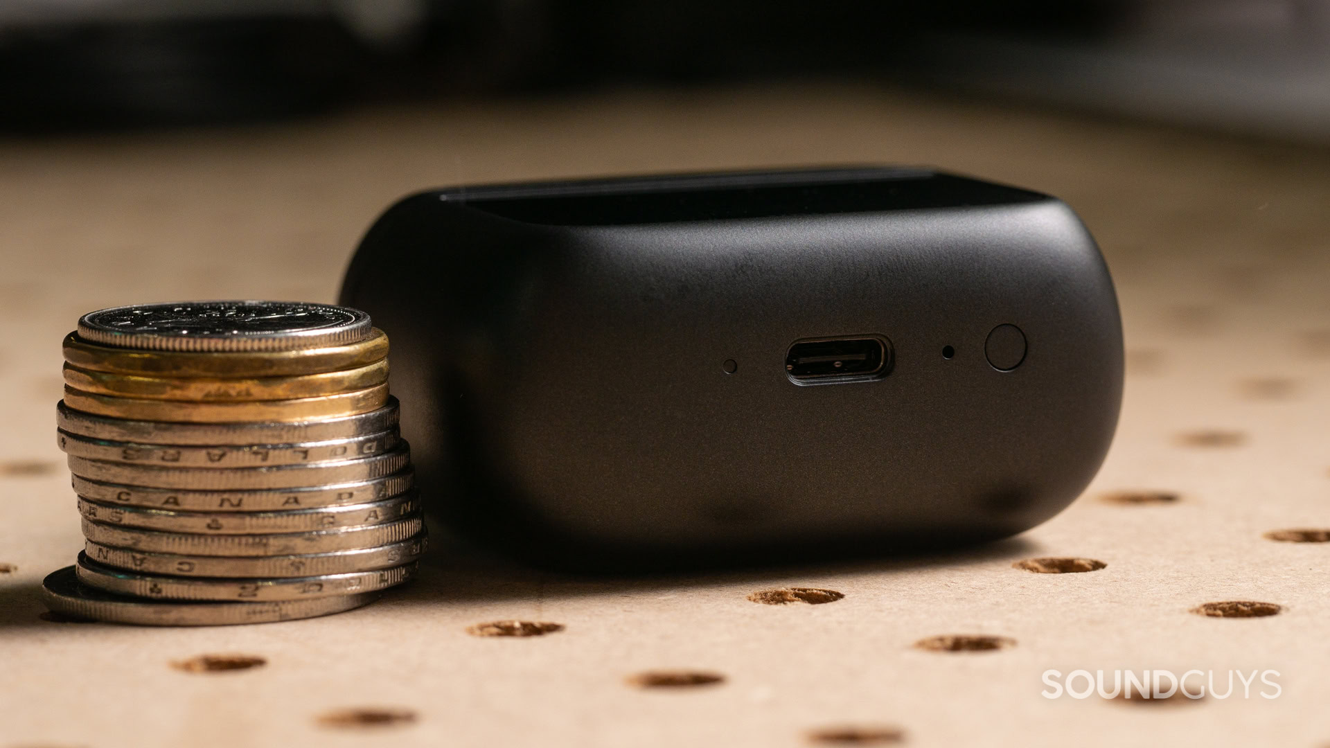 jbl-tour-pro-3-case-thick A photo of the JBL Tour Pro 3's Smart Charging Case, next to a stack of coins.